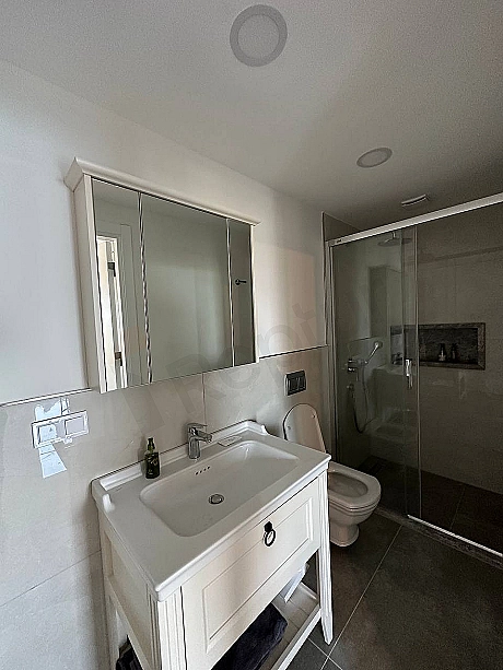 Modern armatürler ve şık detaylarla tasarlanmış, geniş ve eşyalı bir banyo iç mekan görünümü.