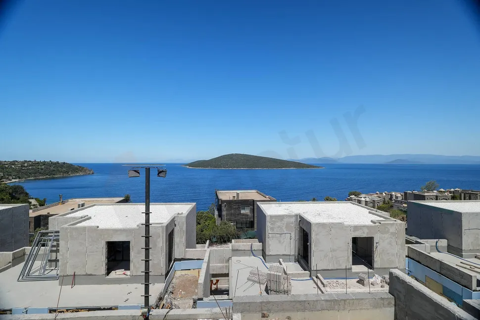 Bodrum'da masmavi bir deniz manzarasını ve sahil şeridini gösteren geniş açılı dış mekan çekimi.