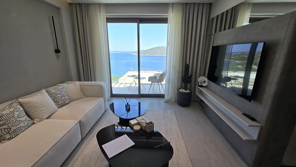 Geniş pencereli, deniz manzaralı ve modern mimariye sahip aydınlık oturma odası.