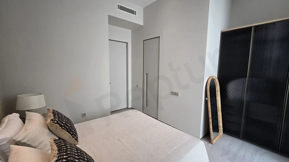 Modern mimariye sahip, geniş pencereli ve gün ışığı alan boş bir yatak odası görünümü.