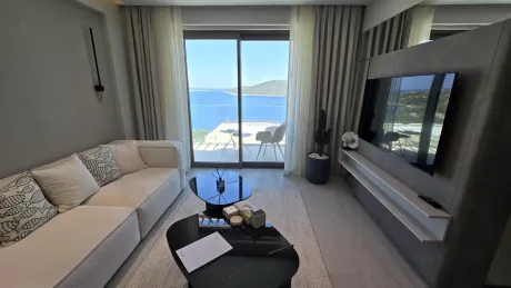 Modern mimariye sahip, geniş pencereli ve ferah bir villa oturma odası alanı.