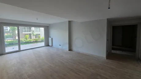 Geniş pencereli, aydınlık ve modern mimariye sahip boş bir oturma odası alanı.