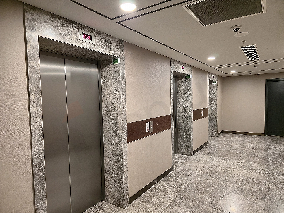 Modern asansör kabini iç mekanı, paslanmaz çelik detaylar, aydınlatma ve kontrol paneli.