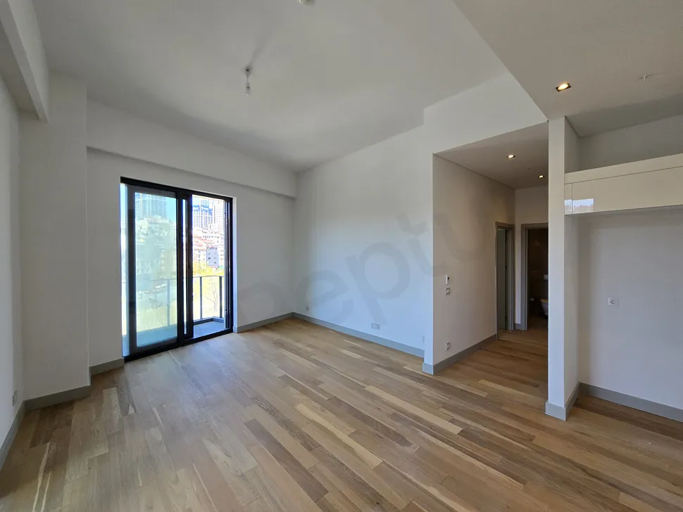 Geniş pencereli, aydınlık ve modern tasarımlı bir oturma odası görünümü.