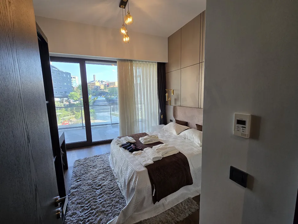 Geniş pencereli, modern tasarımlı ve aydınlık bir yatak odası alanı.