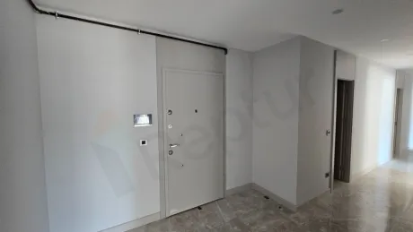 Modern bir binada yer alan dairenin giriş kapısı ve antre alanı.