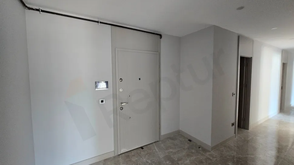 Modern bir binada yer alan dairenin giriş kapısı ve antre alanı.
