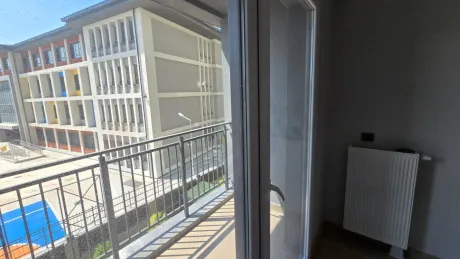 Modern bir binada yer alan geniş balkon alanı ve şehir manzarası.