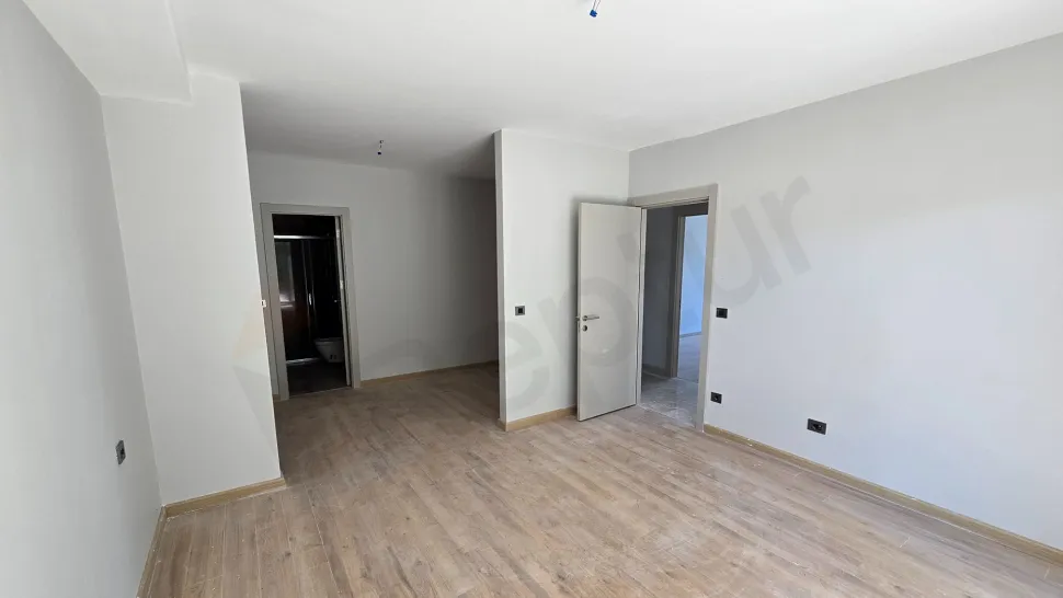 Modern ve ferah tasarımlı, geniş pencereli bir yatak odası görünümü.