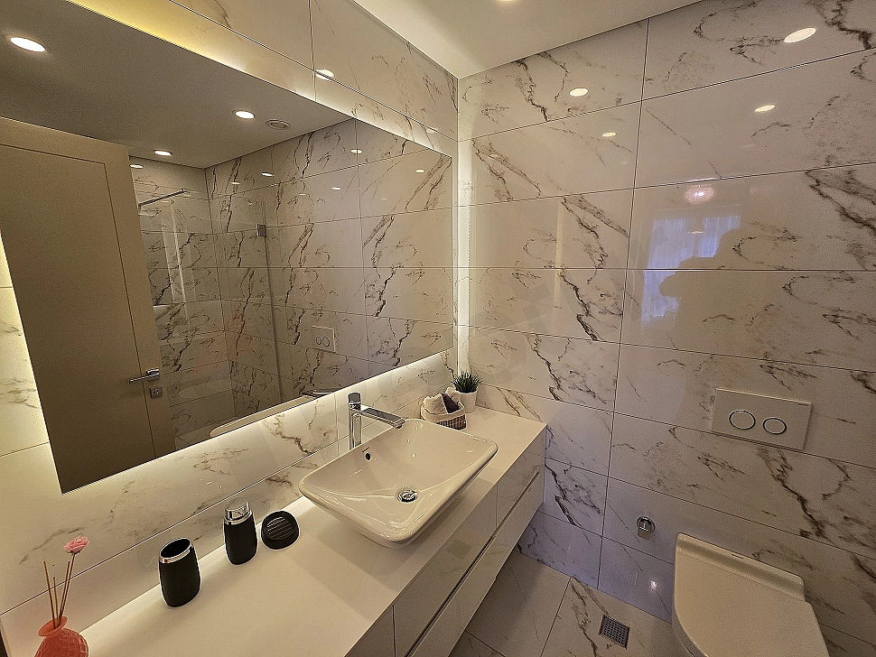 Modern tasarımlı, geniş ve aydınlık banyo. Beyaz seramikler, duşakabin ve şık lavabo.