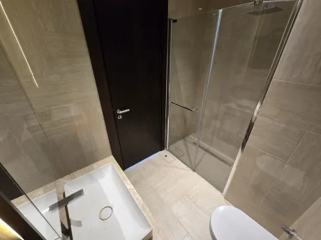 Modern ve şık tasarıma sahip, geniş aynalı ve yüksek kaliteli seramik döşemeli banyo.