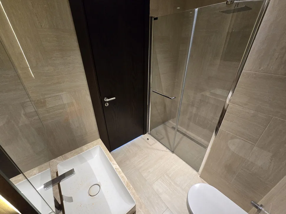 Modern ve şık tasarıma sahip, geniş aynalı ve yüksek kaliteli seramik döşemeli banyo.