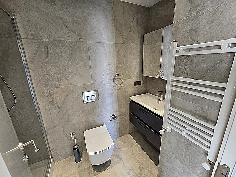 Modern tasarımlı, beyaz seramikli ve geniş aynalı lüks banyo.