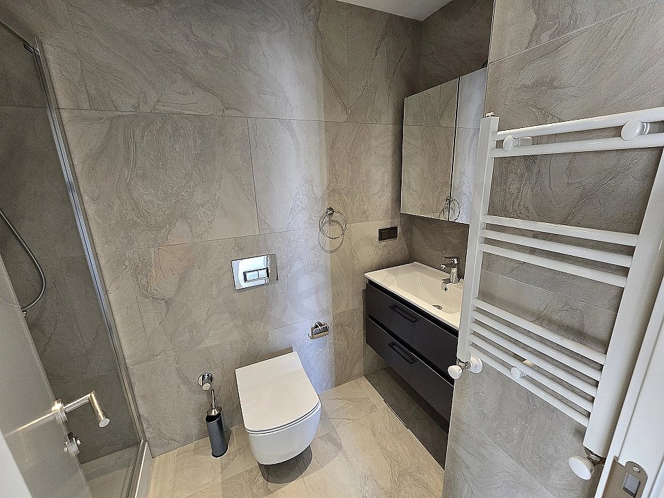 Modern tasarımlı, beyaz seramikli ve geniş aynalı lüks banyo.