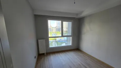 Modern mimariye sahip, geniş pencereli ve gün ışığı alan boş bir yatak odası görünümü.