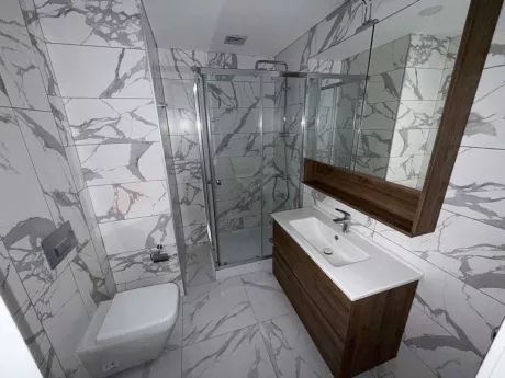 Modern tasarımlı, şık fayanslar ve vitrifiye ürünleri ile donatılmış geniş bir banyo iç mekanı.