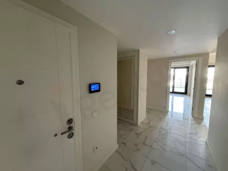 Modern bir binada yer alan dairenin giriş kapısı ve antre bölümü.