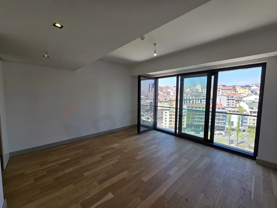 Şişli'deki lüks bir projenin modern ve geniş pencereli boş oturma odası alanı.