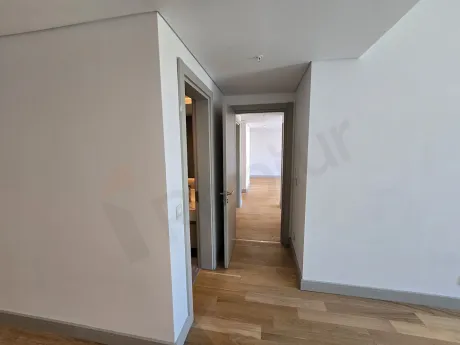 Modern bir binada yer alan, geniş ve aydınlık daire içi koridor görünümü.