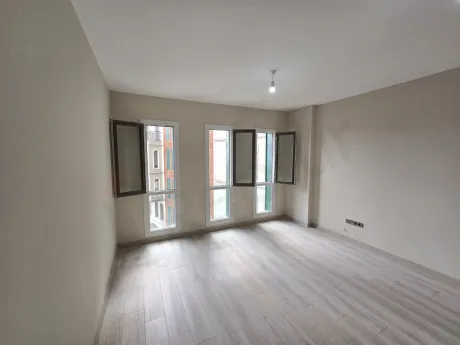 Modern ve ferah bir mimariye sahip, geniş pencereli boş stüdyo daire oturma odası alanı.