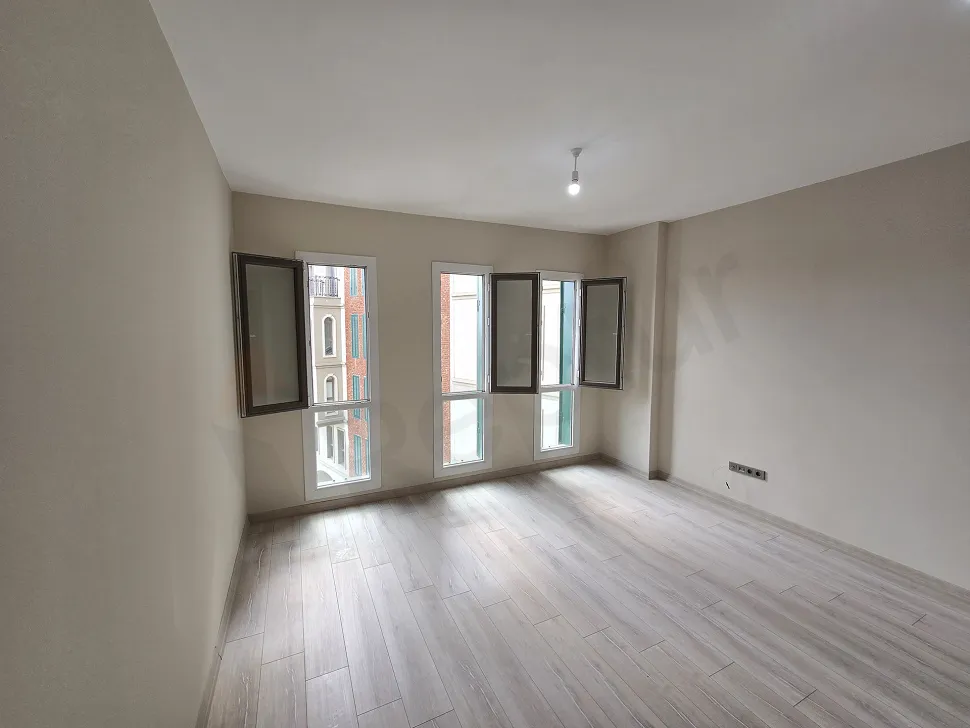 Modern ve ferah bir mimariye sahip, geniş pencereli boş stüdyo daire oturma odası alanı.