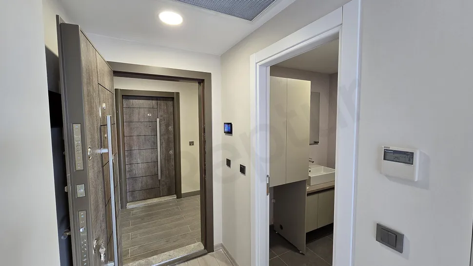 Modern bir dairenin giriş kapısı ve antre alanı görünümü.