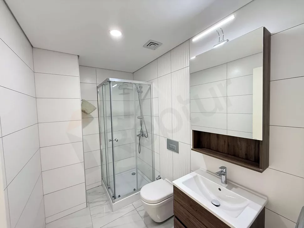 Modern tasarımlı, geniş aynalı ve şık dolaplı banyo iç mekanı.