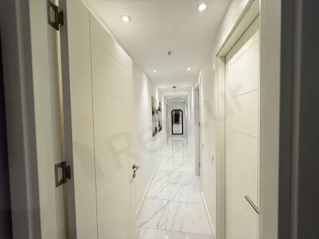 Modern bir binanın iç mekanında yer alan geniş ve aydınlık koridor görünümü.