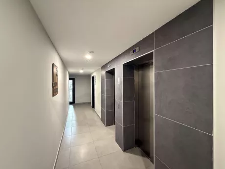 Modern bir binanın iç mekanında yer alan paslanmaz çelik asansör kapısı ve dijital gösterge paneli.