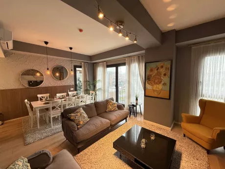 Modern mobilyalarla dekore edilmiş, geniş pencereli ve ferah bir oturma odası görünümü.