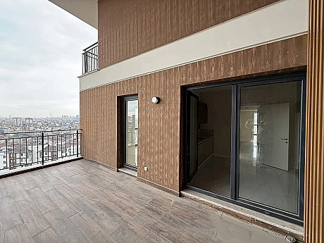 Modern zemin döşemesine ve korumalı korkuluklara sahip, şehir ve orman manzarasına bakan geniş bir daire terası.
