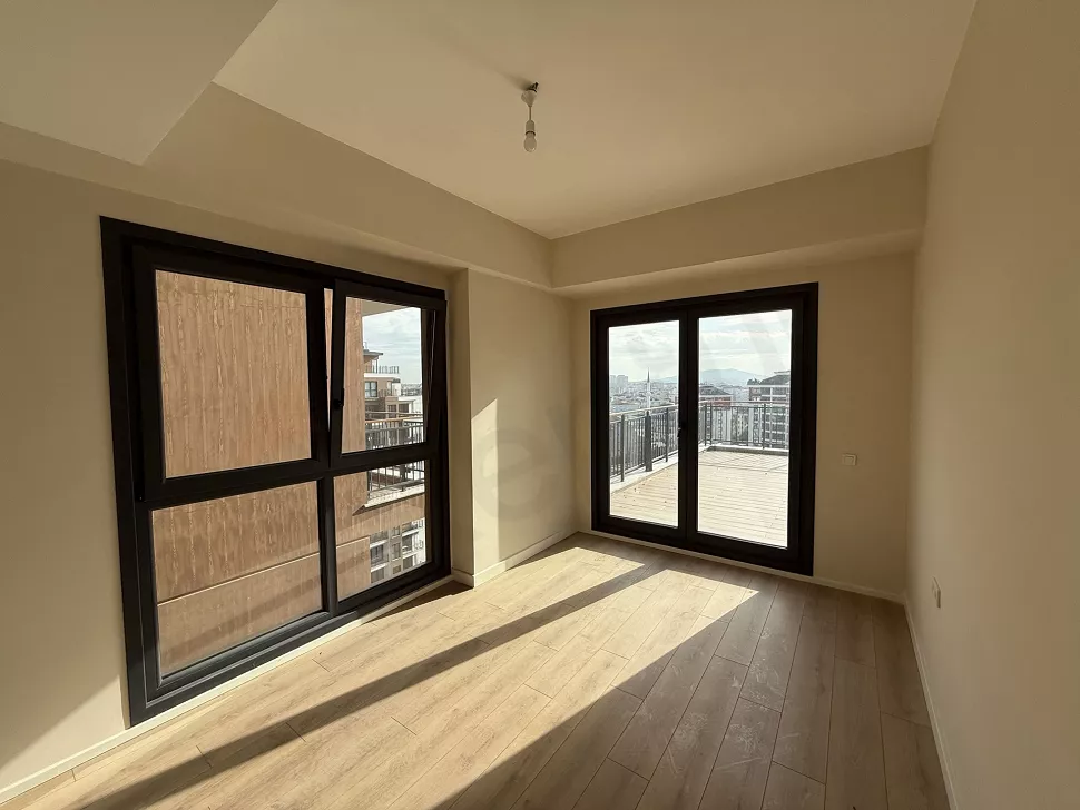 Geniş pencereli, modern zeminli ve aydınlık bir yatak odası alanı.