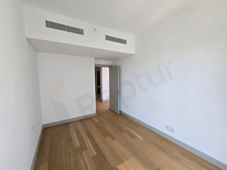 Modern bir rezidans dairesinin geniş ve gün ışığı alan boş yatak odası.