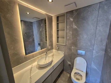 Modern tasarımlı, şık armatürlerin bulunduğu bir banyo iç mekanı.