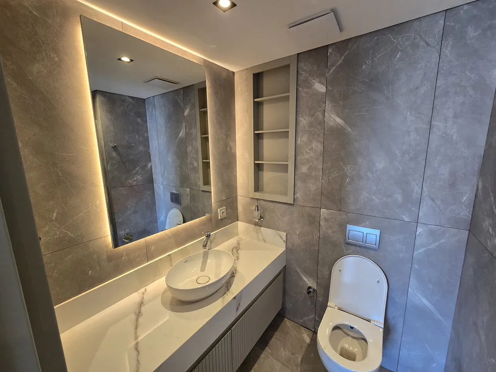 Modern tasarımlı, şık armatürlerin bulunduğu bir banyo iç mekanı.