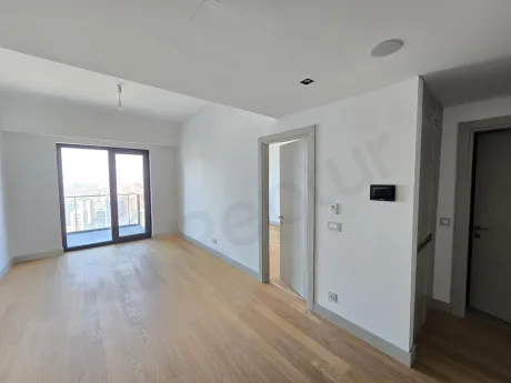 Geniş pencereli, aydınlık ve şehir manzaralı modern bir oturma odası iç mekanı.