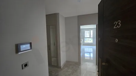 Modern bir binada yer alan geniş ve aydınlık daire koridoru.