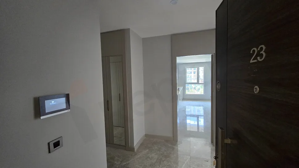 Modern bir binada yer alan geniş ve aydınlık daire koridoru.