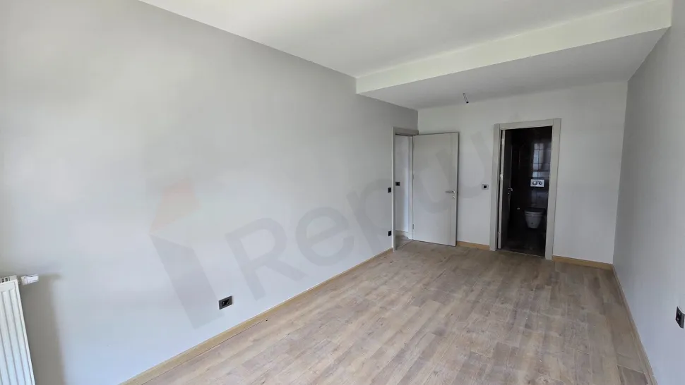 Geniş pencereli, modern tasarımlı ve şehir manzaralı aydınlık bir yatak odası görseli.