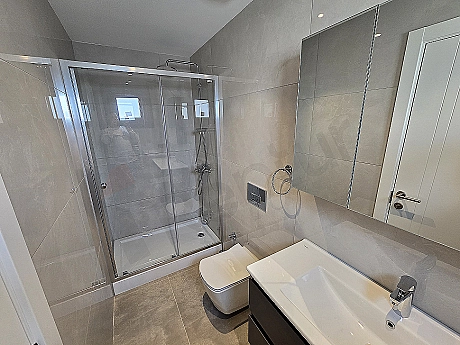 Modern tasarımlı, beyaz seramikli, aynalı ve aydınlatmalı şık banyo.