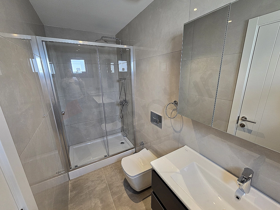 Modern tasarımlı, beyaz seramikli, aynalı ve aydınlatmalı şık banyo.