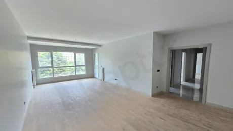 Modern ve ferah tasarıma sahip, geniş pencereli aydınlık bir oturma odası alanı.
