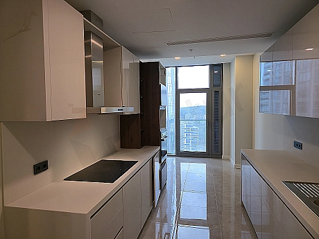 Modern beyaz mutfak dolapları, ahşap tezgah, ankastre fırın ve ocak içeren ferah mutfak.