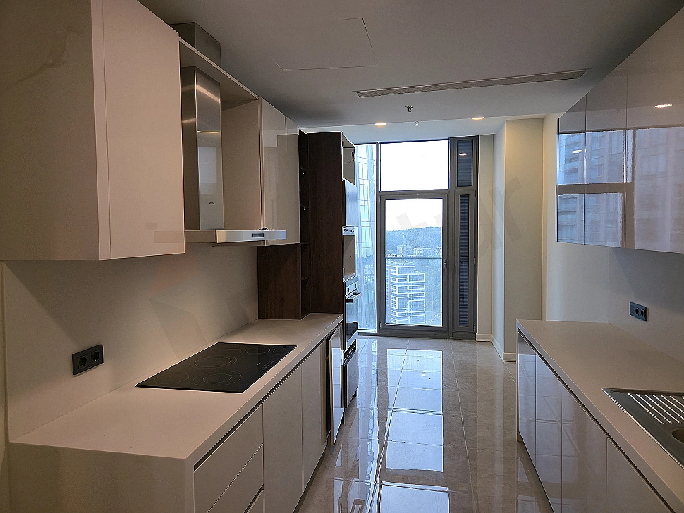 Modern beyaz mutfak dolapları, ahşap tezgah, ankastre fırın ve ocak içeren ferah mutfak.