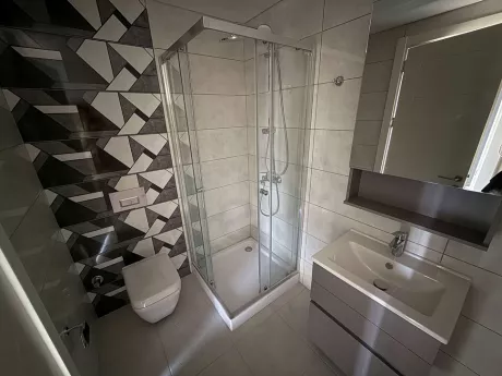 Modern tasarıma sahip, şık seramiklerle döşenmiş banyo ve lavabo alanı.