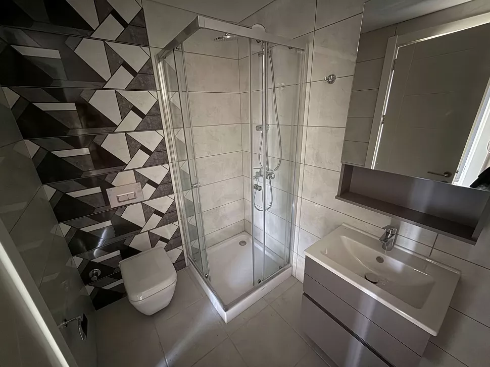 Modern tasarıma sahip, şık seramiklerle döşenmiş banyo ve lavabo alanı.