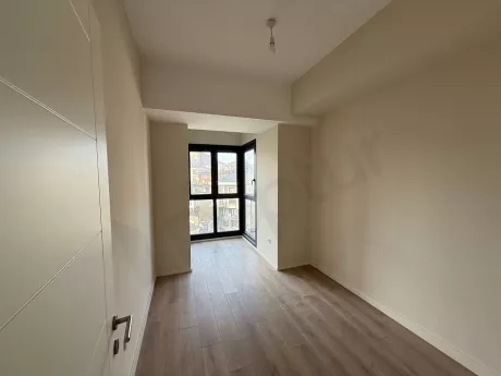 Geniş pencereli, aydınlık ve modern tasarımlı yeni bir dairenin yatak odası görünümü.