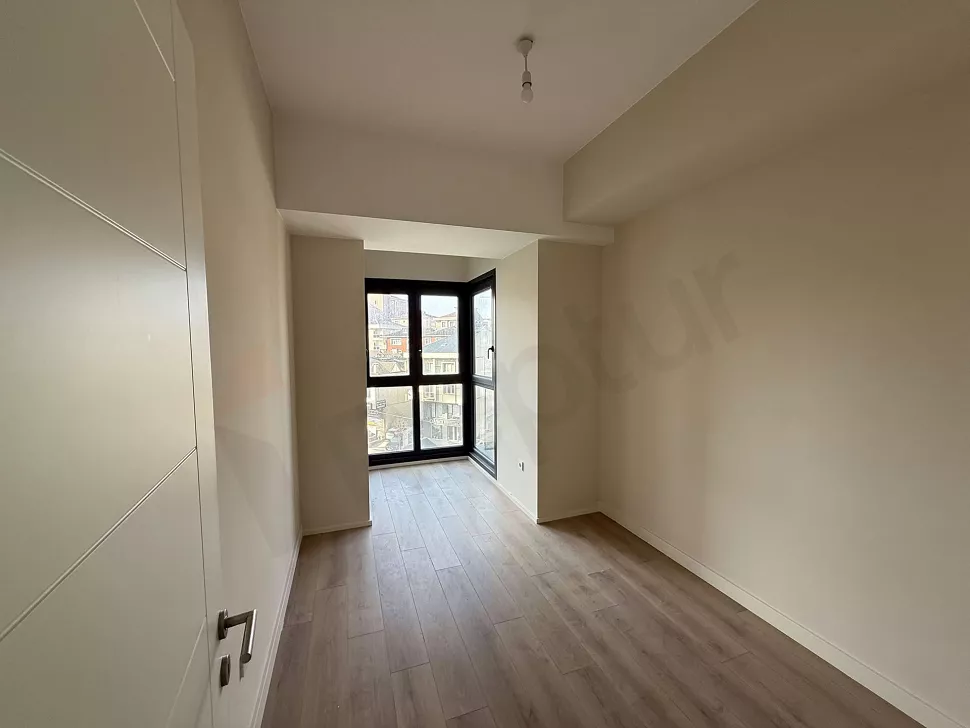 Geniş pencereli, aydınlık ve modern tasarımlı yeni bir dairenin yatak odası görünümü.