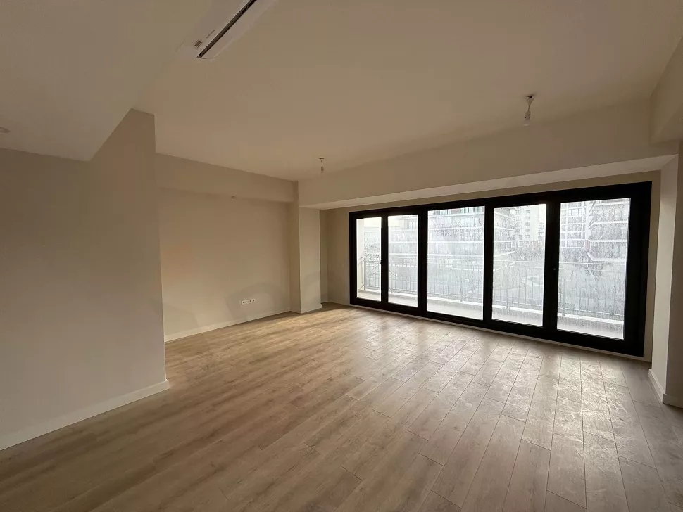 Gün ışığı alan, modern tasarımlı, geniş pencereli ve ferah bir oturma odası.
