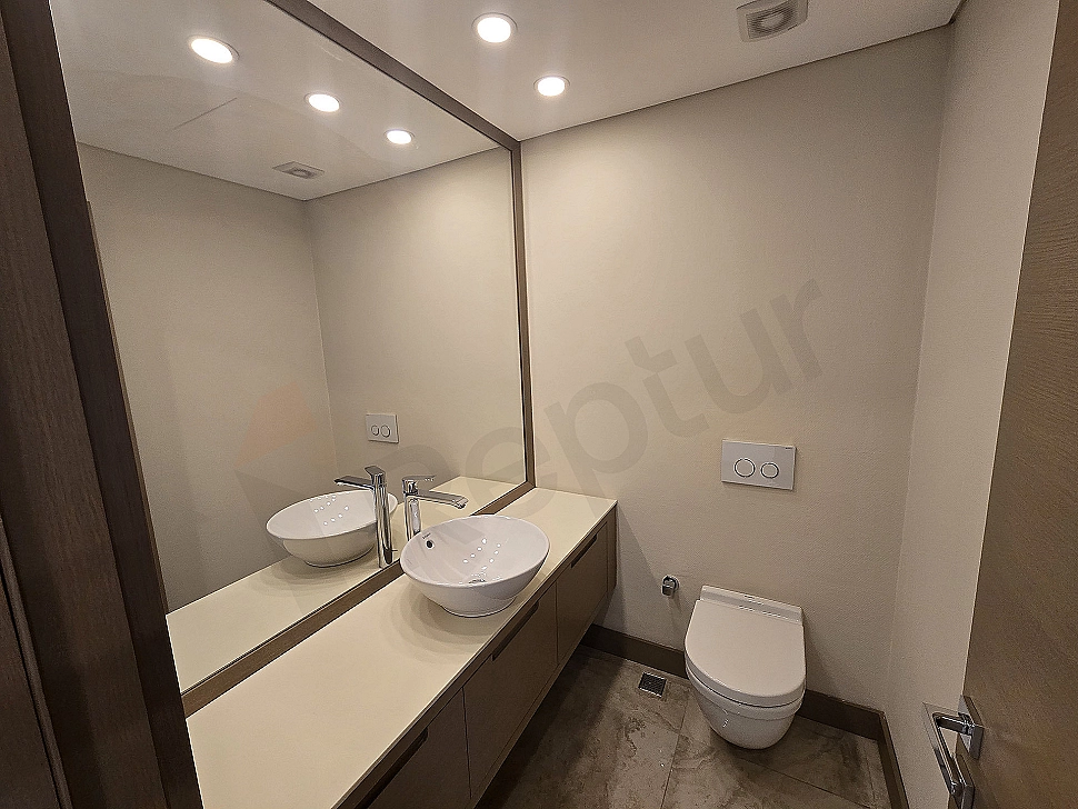 Modern tasarımlı, lüks detaylara sahip dubleks daire banyo görseli. Beyaz seramikler, geniş duşakabin ve şık aydınlatma.